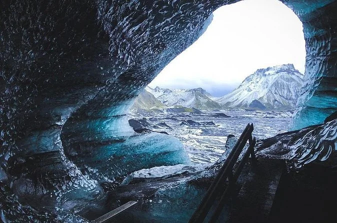 An ice cave opening framing the mountains outside