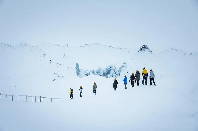 Un grupo caminando en fila sobre un glaciar nevado en invierno